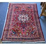 A Persian hand woven red ground rug having a central motif with multiguard borders, 156cm x 108cm