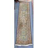 A hand woven silk runner having floral motifs and a beige ground, 189cm x 47cm Location: