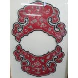 A Chinese Qing Dynasty red silk cloud collar embroidered in a green and pink thread depicting images