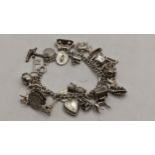 A silver chain link charm bracelet with mixed charms to include Big Ben, coins and others, 66.2g