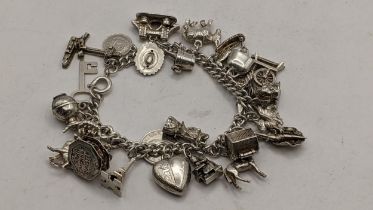 A silver chain link charm bracelet with mixed charms to include Big Ben, coins and others, 66.2g