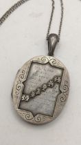 A Victorian white metal oval locket engraved with the prayer of Mizpah and on a white metal chain,