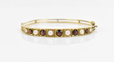 A 9ct yellow gold, pearl and garnet set bangle, set with graduated alternating pearl and red