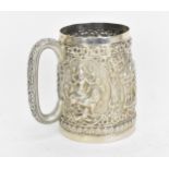 A Colonial Indian white metal mug, possibly Bombay, of tapered form with deep embossed vignettes