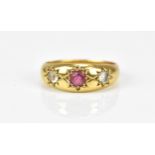 A yellow metal, diamond and ruby gypsy ring, set with central round cut ruby flanked with an old cut