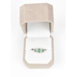 A 14ct white gold, diamond and emerald dress ring, with central oval cut emerald in a halo of