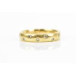 An 18ct yellow gold and scattered diamond contemporary wedding band, set with eight small