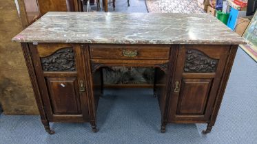 A late Victorian walnut marble topped desk having a single drawer flanked by two carved doors 74h