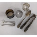 Six pieces of silver to include a spoon, sugar tongs, a pair of nutcrackers and three napkin