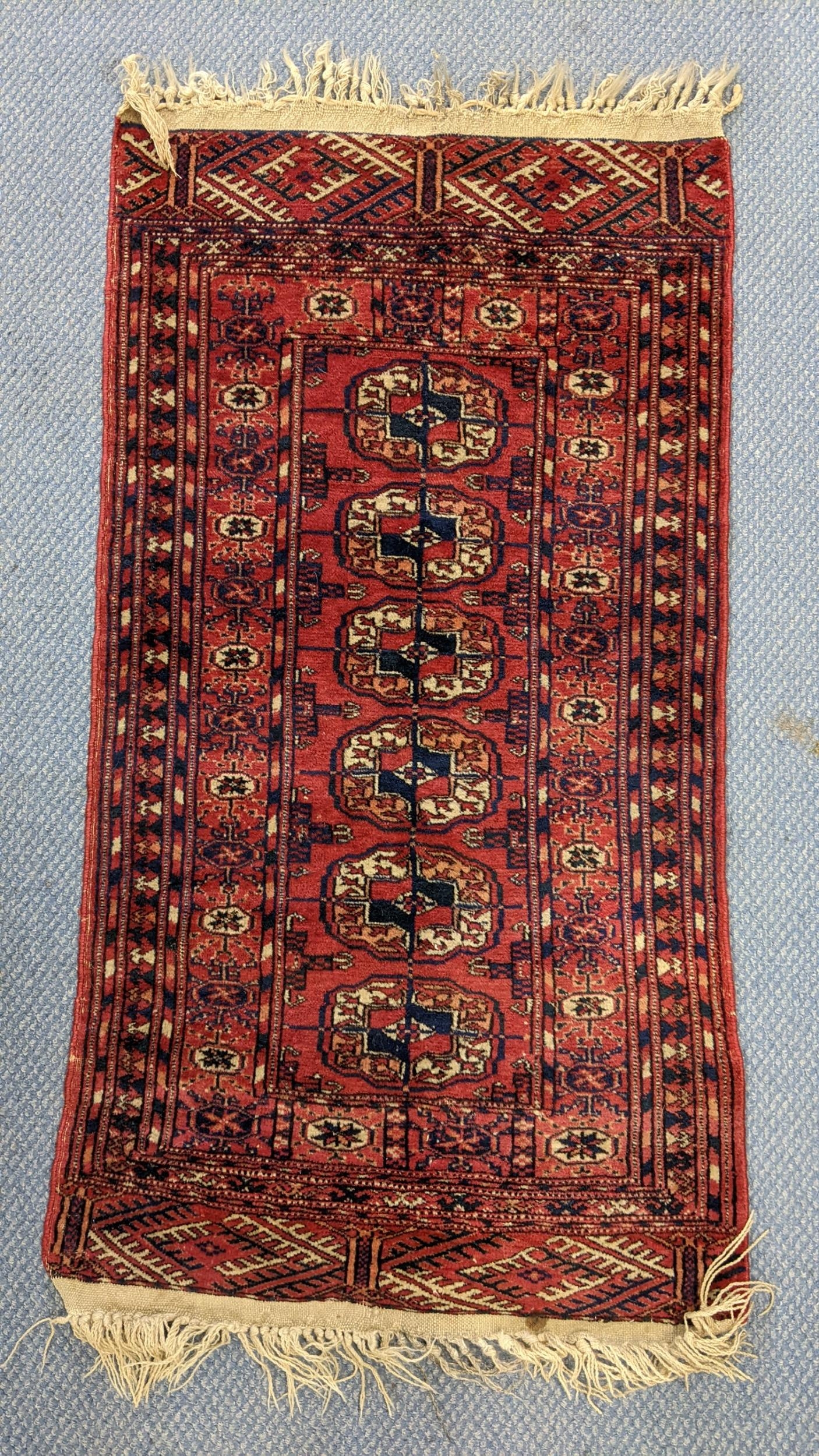 A hand woven Persian design red ground small rug having elephant foot motifs and multiguard borders,