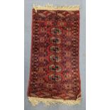 A hand woven Persian design red ground small rug having elephant foot motifs and multiguard borders,