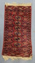 A hand woven Persian design red ground small rug having elephant foot motifs and multiguard borders,