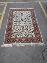 A Persian Tabriz rug with a red floral border, and a symmetrical design with plants and flowers in