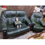 A carved wooden framed and green leatherette upholstered two-seater sofa and matching armchair,
