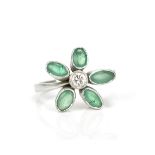 A white metal, emeralds and diamond floral ring, with central bezel set brilliant cut diamond in a