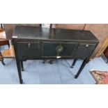 An Oriental black lacquered console table having drawers flanking two cupboard doors, 81.5cm h x