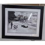 A black and white reprinted photograph of Stirling Moss in a car, signed Location:
