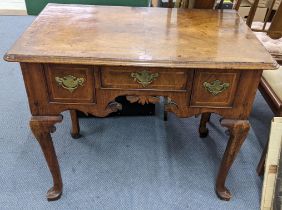 An early 18th century quarter cut veneered walnut lowboy having three drawers and a carved apron 70h