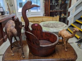 A wooden Chinese baby bath with shaped bird head handle, along with two leather camel models