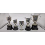 Five miniature silver cups including two twin handled examples, one on a stand and three other