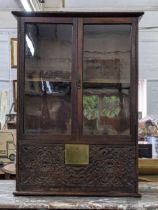 An 18th century and later oak cabinet with twin glazed doors and a carved fall front, 89cm h
