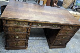 A late Victorian/Edwardian oak twin pedestal desk, one long flanked by two short frieze drawers,