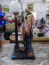 A large painted fibreglass table lamp fashioned as a clown next to a street lamp Location: