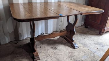 An early 20th century oak fall flap table having a swivel top and two shaped pedestals, 61cm h x