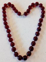 A vintage necklace of 37 cherry amber beads on string having a 9ct gold clasp. Location:Cab