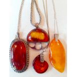 Four modern amber pendants on silver tone mounts and silver tone chains (no hallmarks) to include