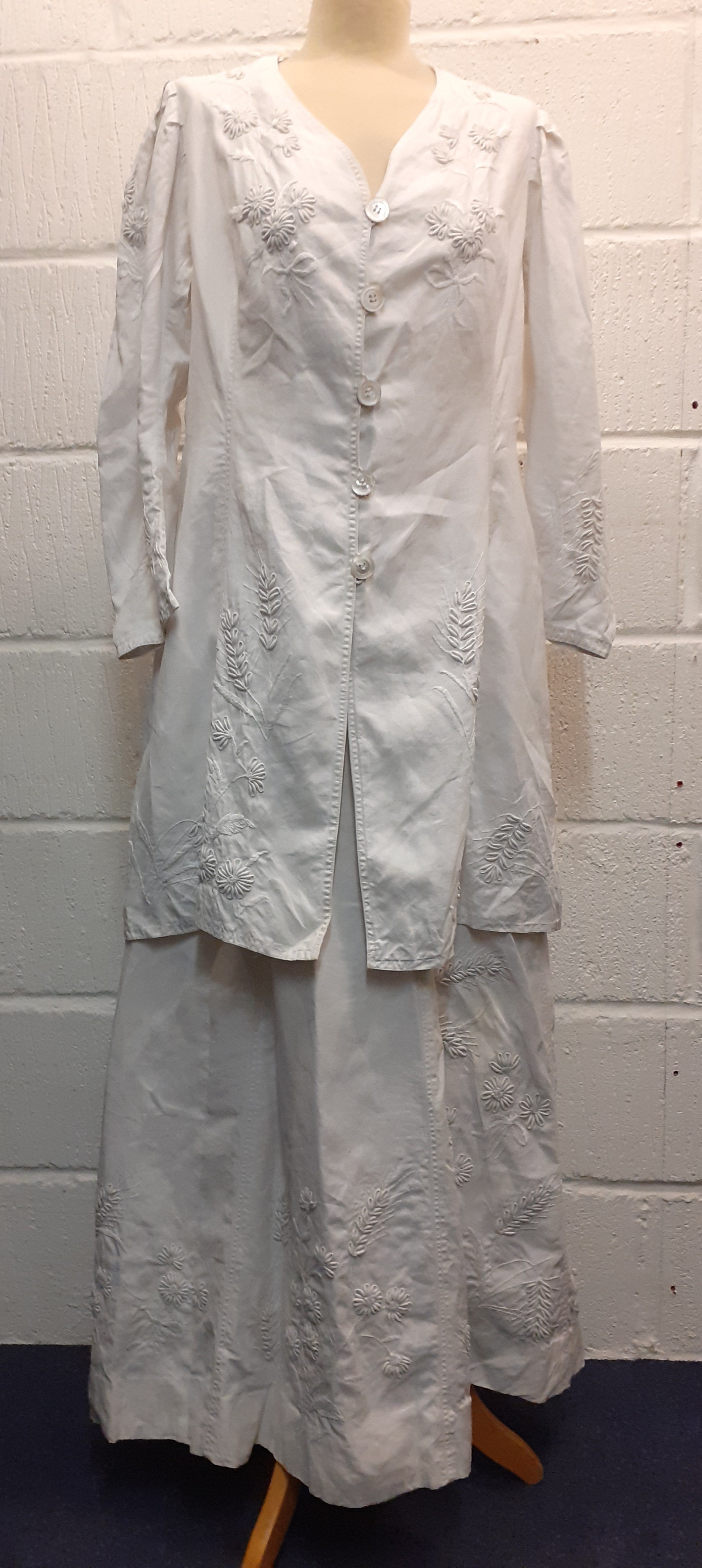 A late 19th/ early 20th Century white cotton and embroidered driving outfit comprising a longline