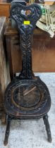 An early 20th century carved oak spinning chair and a bras veritas oil lamp with a cranberry