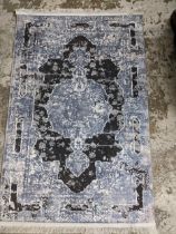 A contemporary machine woven polyester filament rug in grey and black, tasselled ends 160 x 99cms