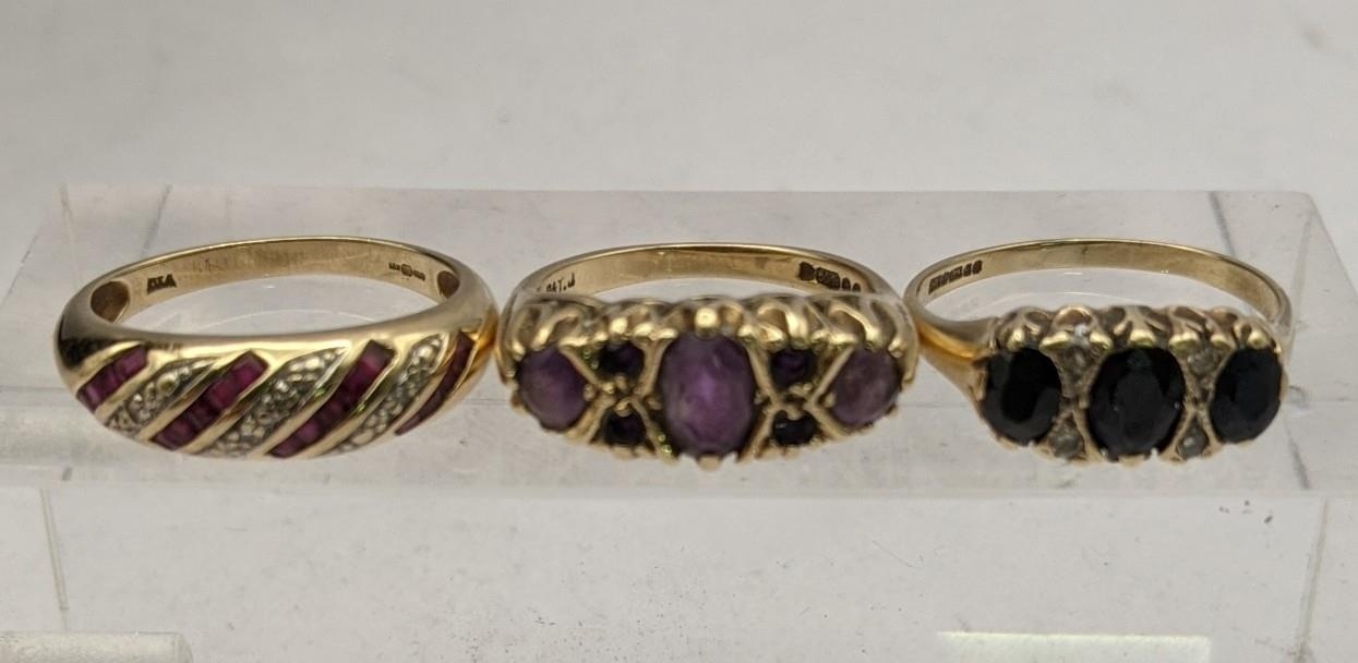 Three 9ct gold rings to include a diamond and ruby bomb ring, a ring set with amethysts and one