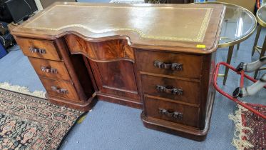 A Victorian mahogany leather topped desk having a serpentine drawer with cupboard below, flanked