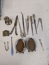 Silver handled button hooks, glove stretcher, sugar tongs, dwarf candlestick, manicure item and