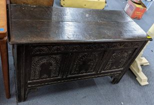 A late 17th/early 18th century oak panelled coffer having a carved front and inset candle box, 66.5h