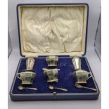 A cased set of four silver salts with glass liners along with four salt spoons and two salt