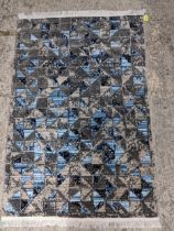 A small contemporary geometrical abstract designed rug in colours of grey, black and blues,