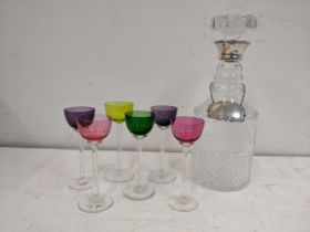 A set of six coloured glass liqueurs, a decanter and silver sherry label Location: