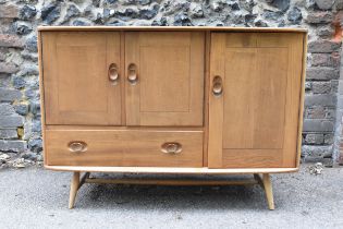 A mid-century Ercol Windsor elm sideboard, with twin-cupboard doors enclosing a shelf, flanked by