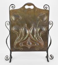 An Arts & Crafts hammered copper fire screen, with embossed stylised motif, pierced handle to the