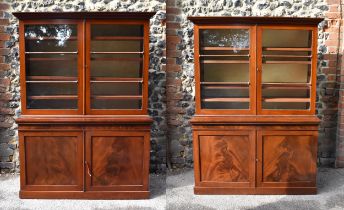 A pair of Victorian flame mahogany bookcases, with moulded cornice, glazed double doors opening to a