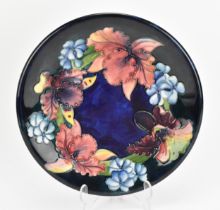 A Walter Moorcroft pottery 'iris' pattern plate, circa 1950, designed with a frieze of blooms