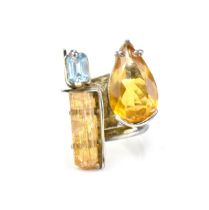 A contemporary silver-mounted citrine, blue topaz and raw imperial topaz dress ring by a Brazilian