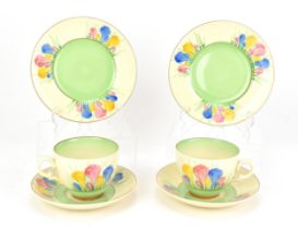 Two Clarice Cliff 'Spring Crocus' pattern trio sets, comprising a tea cup, saucer and side plate,