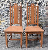 A pair of Edwardian Arts and Crafts entrance hall oak chairs, circa 1910, with pierced detail to the