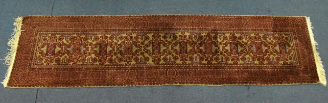 A handwoven Afghan kazak runner, with central geometric pattern against an ochre ground and multiple
