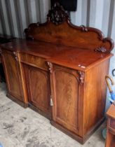 A Victorian mahogany sideboard having a raised carved back, central drawer and three cupboard