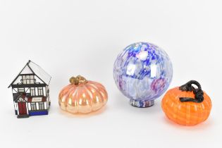 Two hand blown glass pumpkins by Ken and Ingrid Hanson, one in iridescent light orange, the other